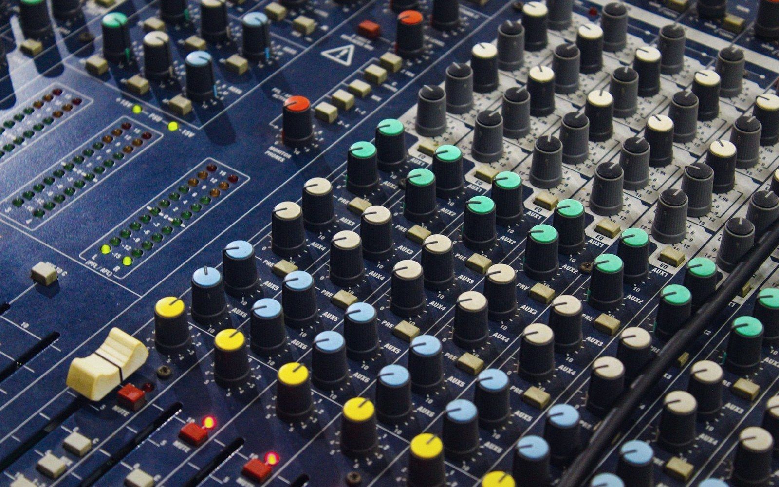 Rows of colorful knobs and sliders on an audio mixing console
