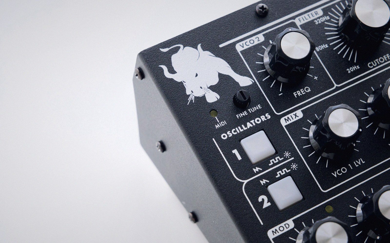 Close-up of a synthesizer's oscillator section with knobs, buttons and a bull logo